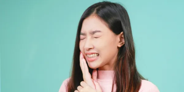 ワイヤー矯正で痛みを感じている女性
